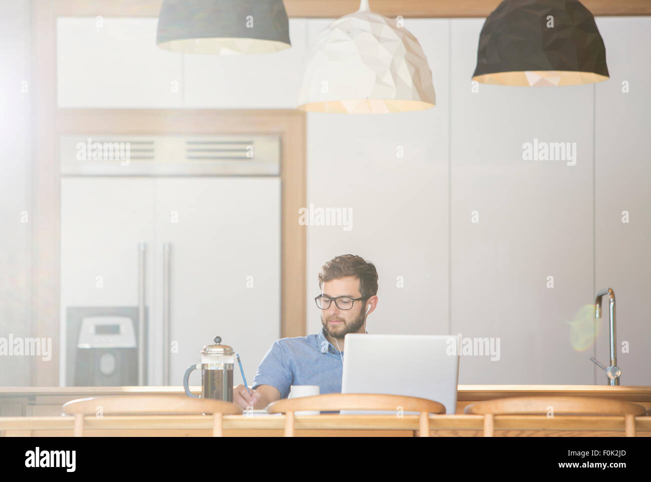 Mann am Laptop in der Küche mit französischen Presse Kaffee schreiben Stockfoto