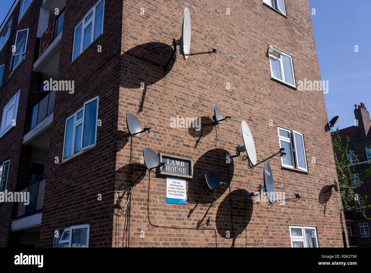 Satellitenschüsseln an der Seite von einem Wohnblock in einem South London Anwesen. Stockfoto