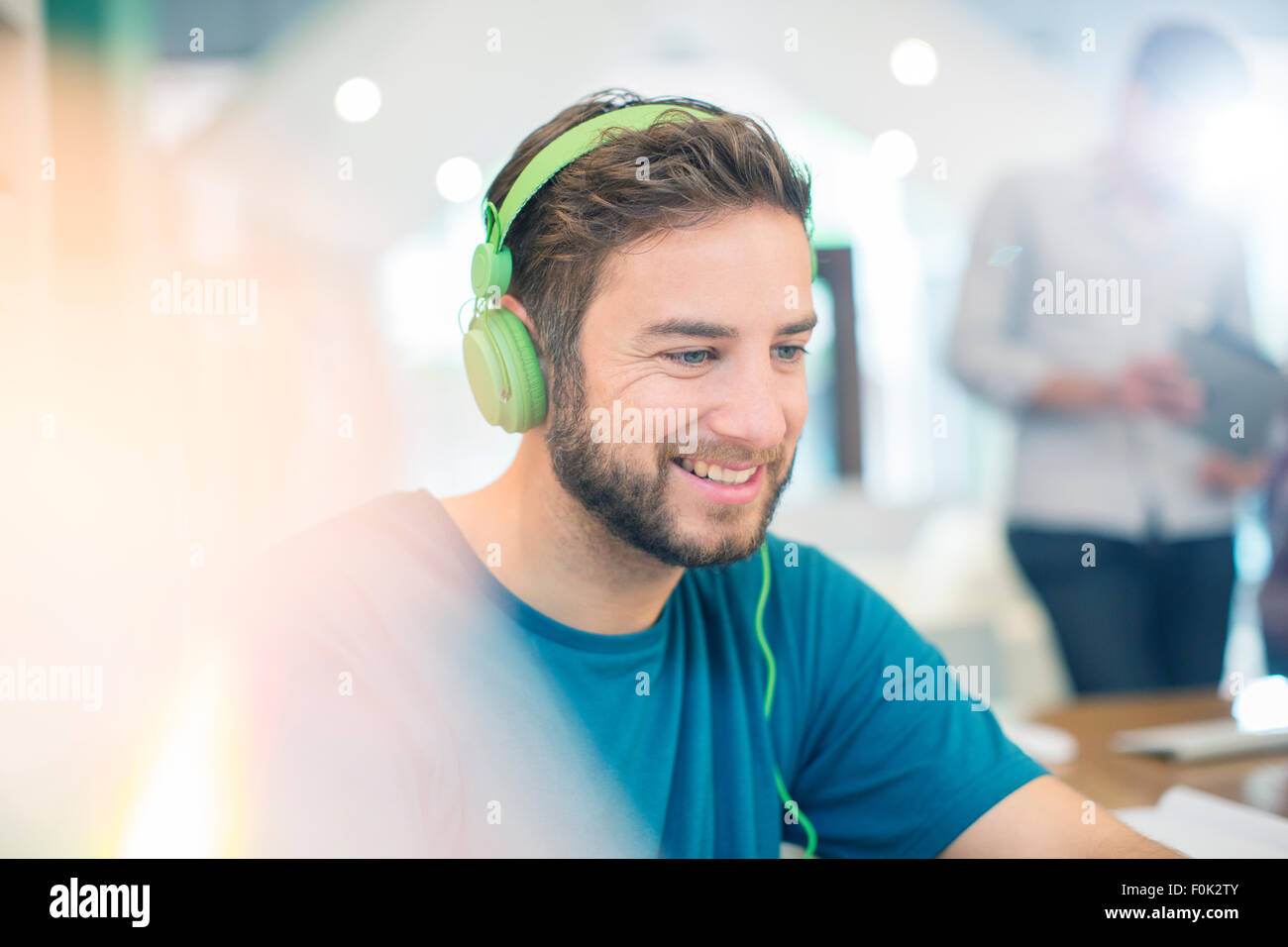 Lächelnde kreative Geschäftsmann hören Kopfhörer im Büro Stockfoto