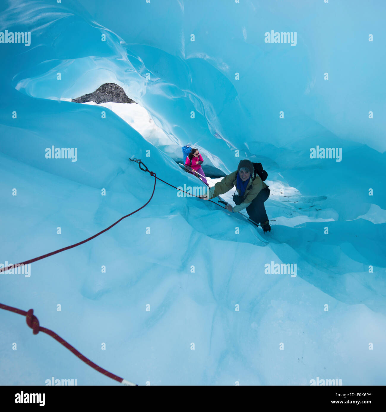 Reife Frauen, Klettern durch eine Eishöhle am Fox-Gletscher, Südinsel, Neuseeland. Stockfoto