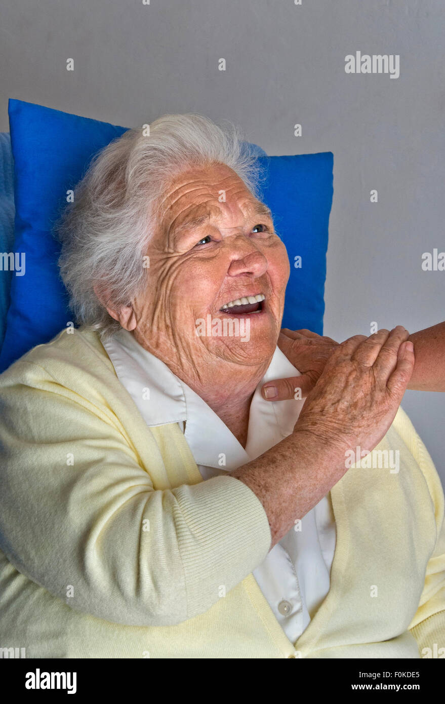 Glückliches Lachen erfüllt ältere Dame hält beruhigend Arm der Pflegeperson Begleiter Stockfoto
