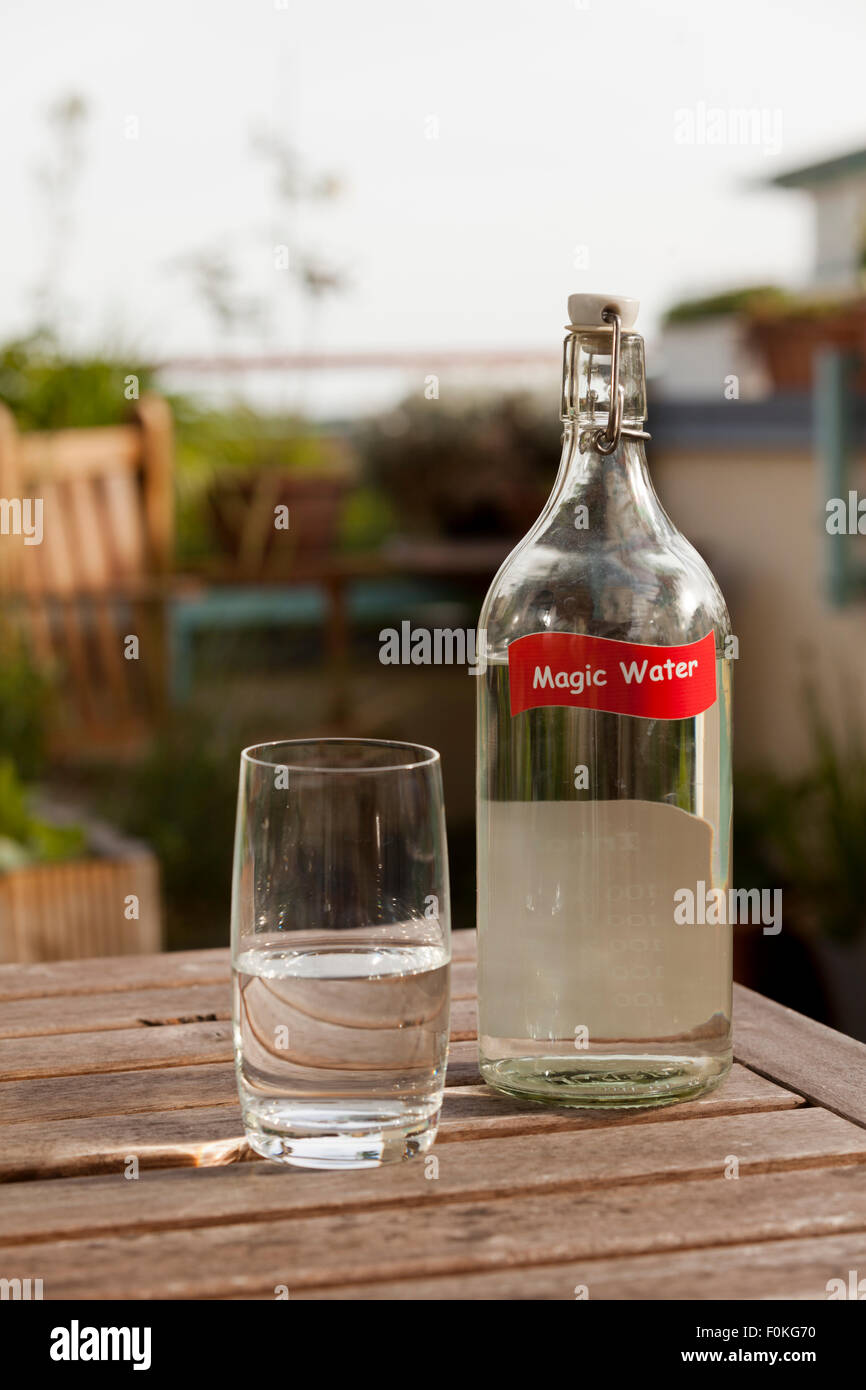 Wasserglas und Flasche auf Tisch im Garten Stockfoto