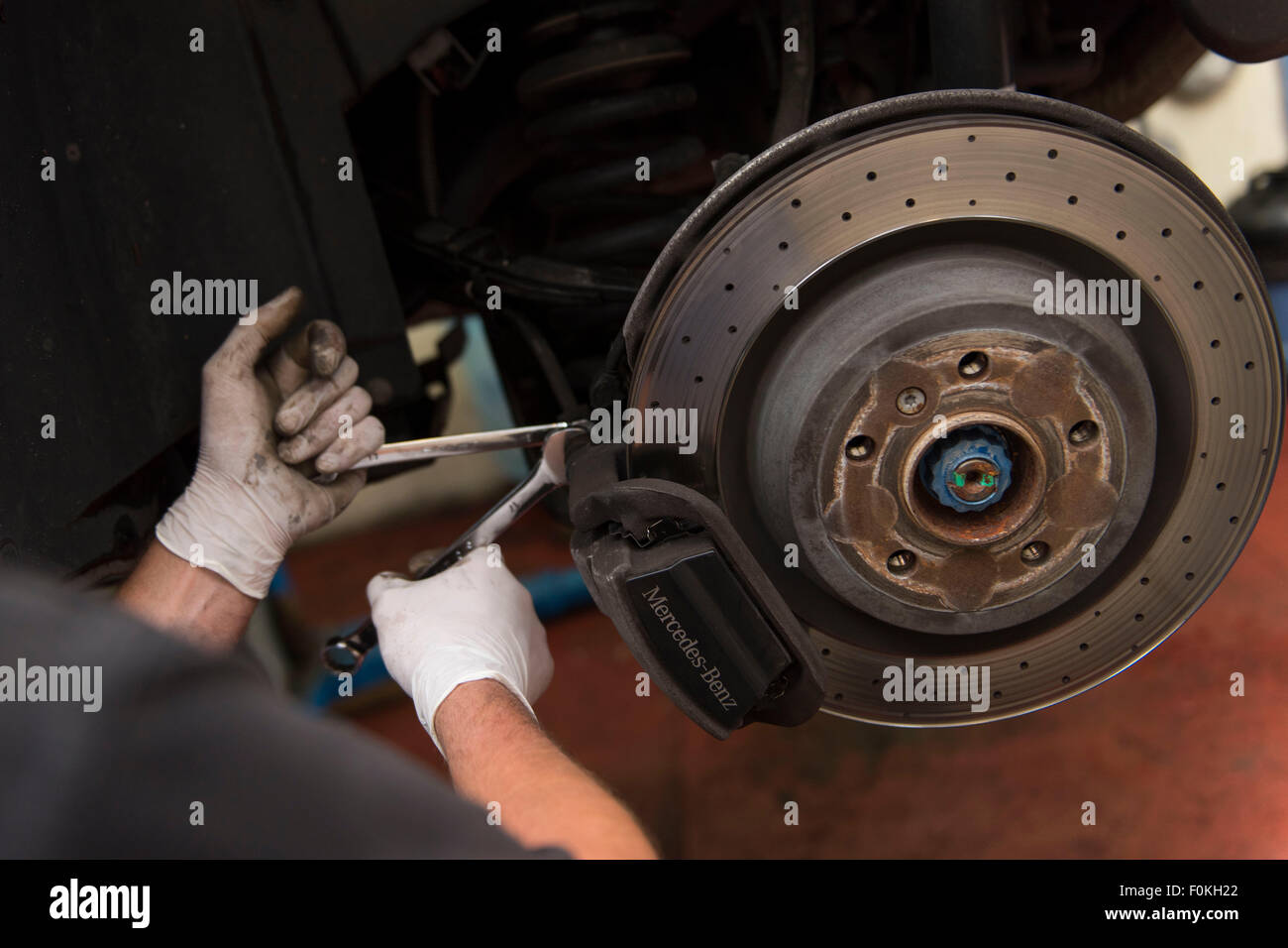Kfz-Mechaniker passt neue Bremsbeläge zu einem Auto in einer Garage während eines MOT. Stockfoto