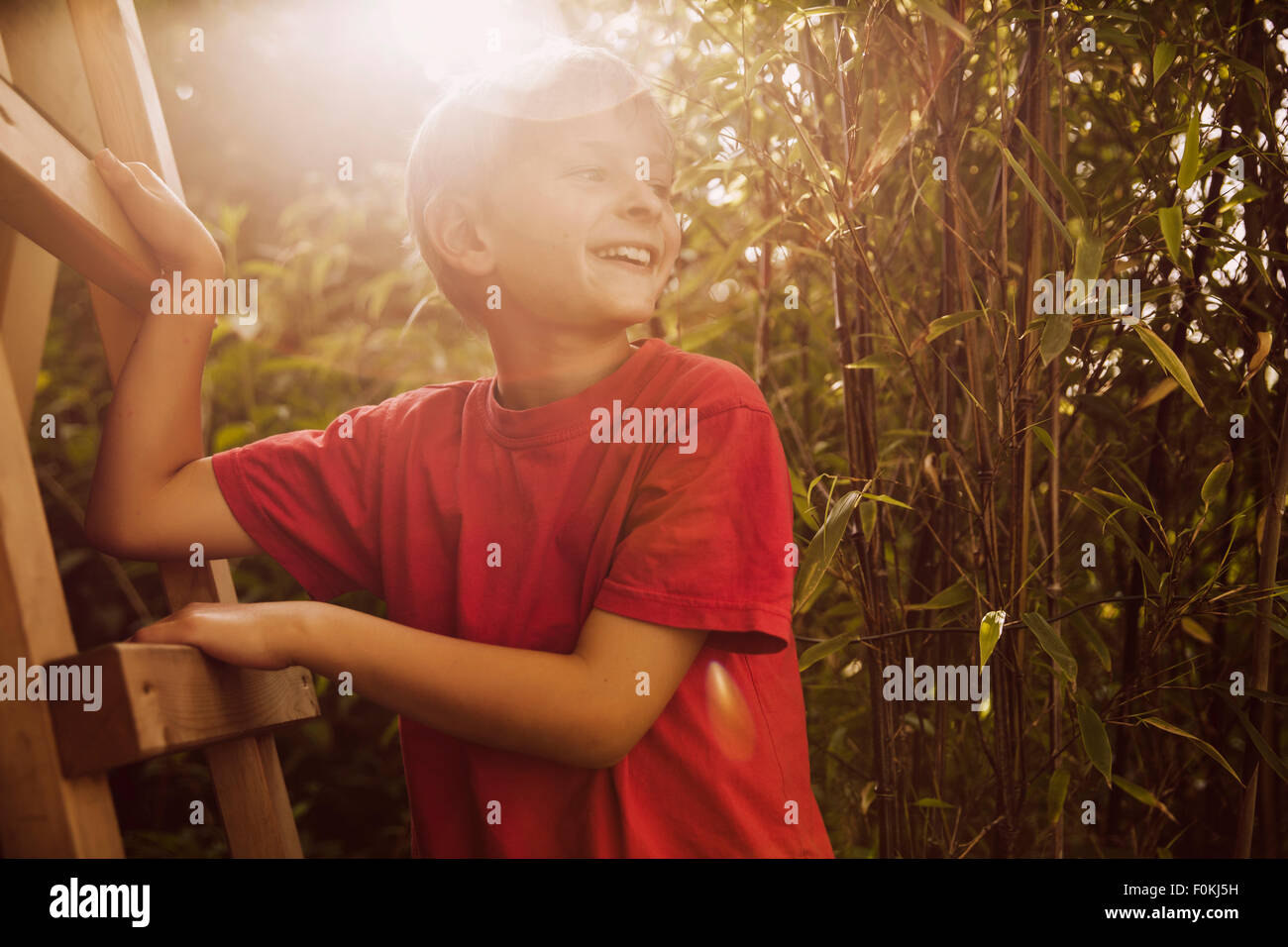 Junge klettert eine Holzleiter in einem Bambusgarten Stockfoto