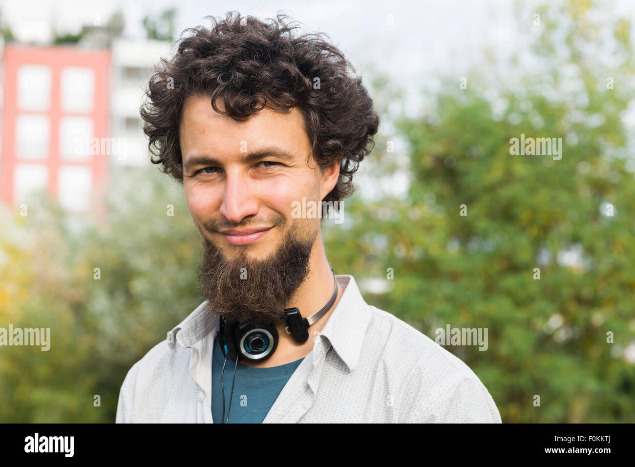 Porträt von lächelnden jungen Mann in einem städtischen Garten Stockfoto