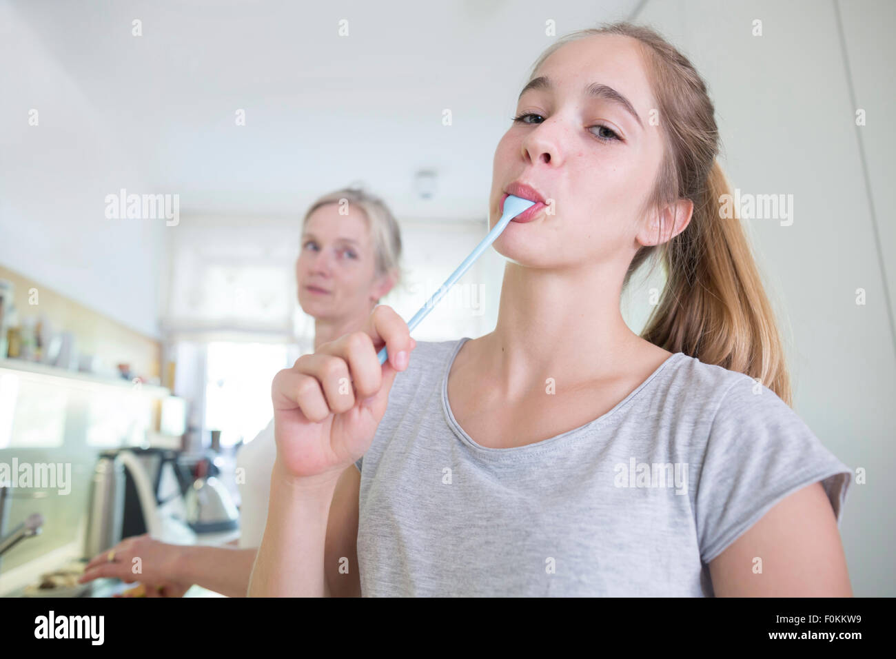 Porträt von Teenager mit Löffel in den Mund in der Küche Stockfoto
