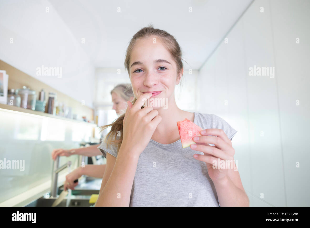 Porträt von lächelnden Mädchens Essen Melone in der Küche Stockfoto