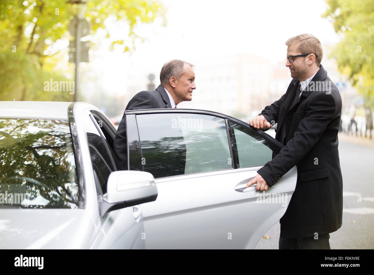 Chauffeur öffnet Autotür für Geschäftsmann raus Stockfoto