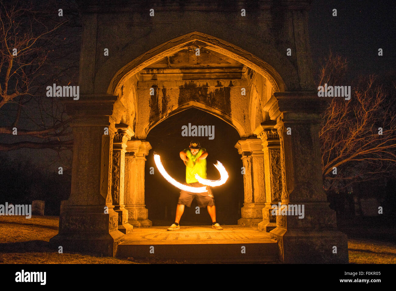 Ein College-Student dreht und jongliert Feuer auf dem Oakwood Cemetery in Syracuse, New York. Stockfoto
