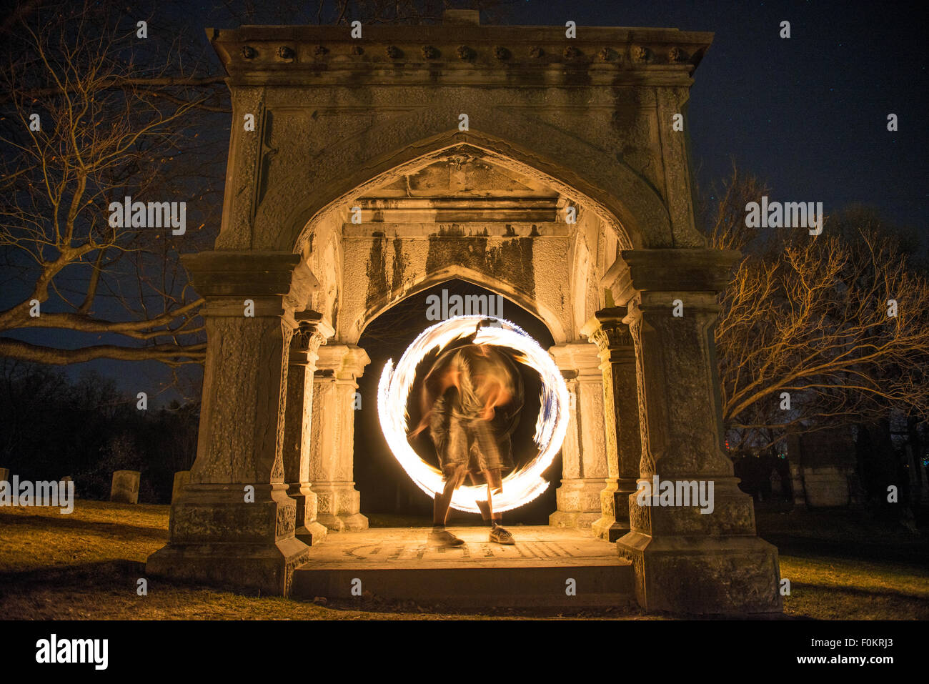 Ein College-Student dreht und jongliert Feuer auf dem Oakwood Cemetery in Syracuse, New York. Stockfoto