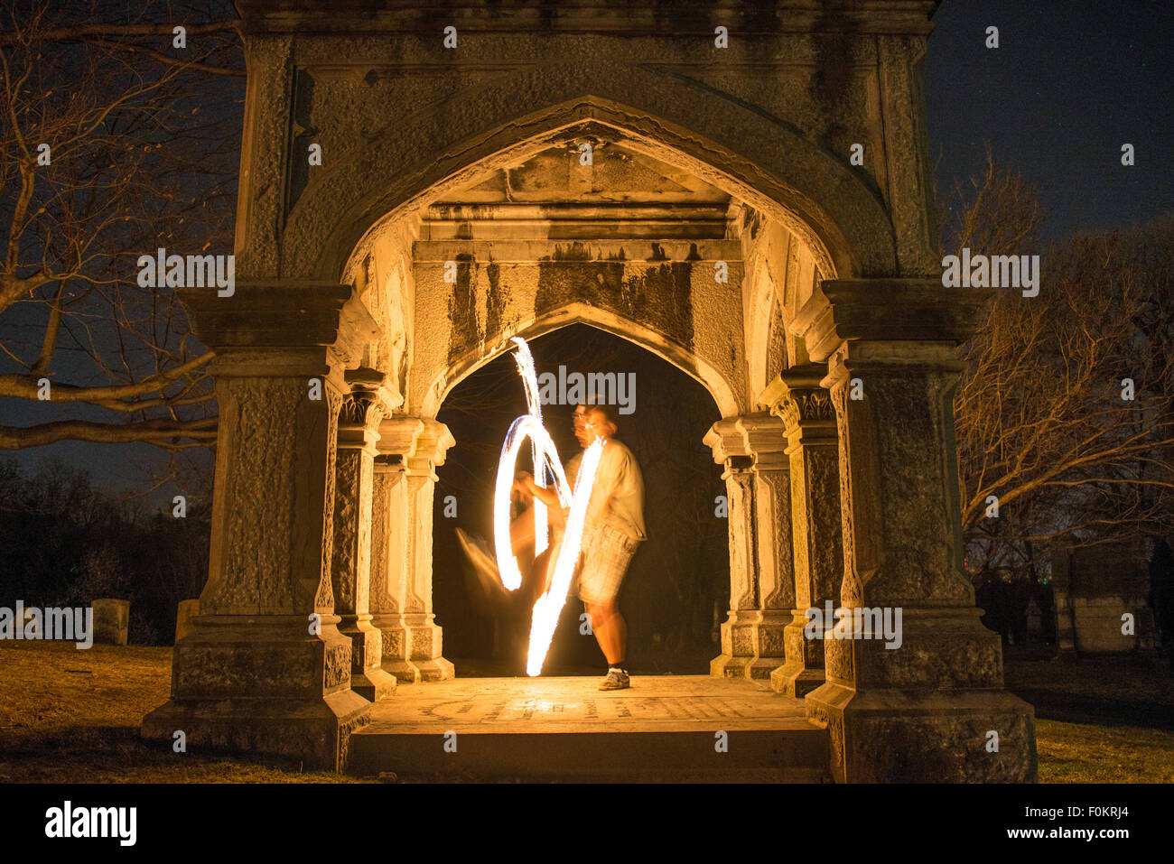 Ein College-Student dreht und jongliert Feuer auf dem Oakwood Cemetery in Syracuse, New York. Stockfoto