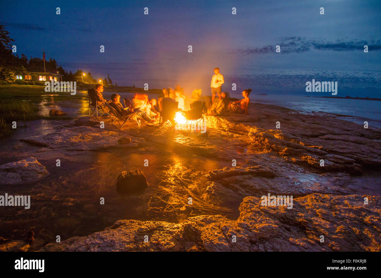 Familie und Freunde Aufwärmen am Lagerfeuer unter einer schwarz gearbeiteten Nacht wie Flut langsam ins Landesinnere rieselt. Stockfoto