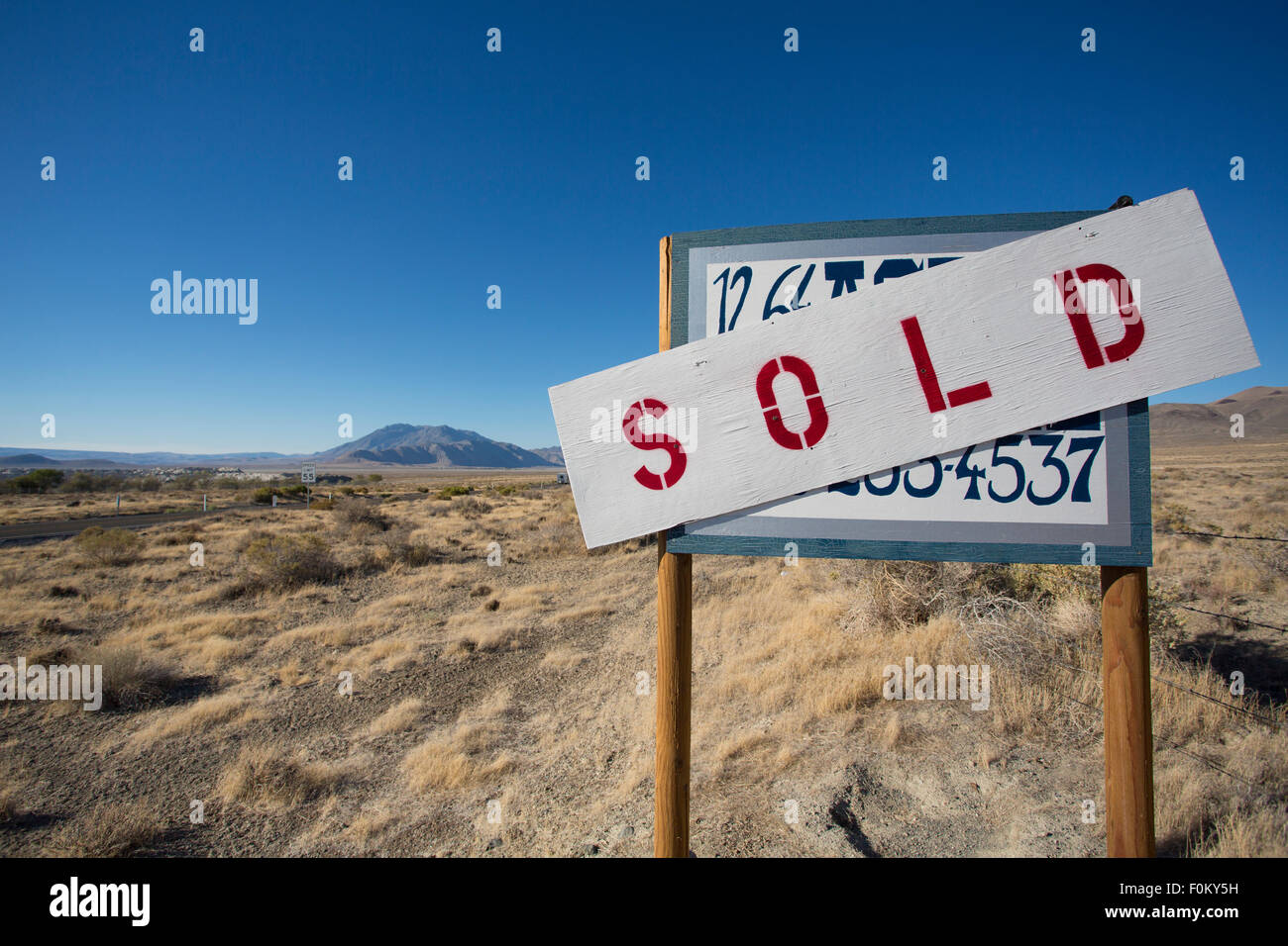 Ein Zeichen für den Verkauf ein Grundstück mitten im nirgendwo in Nevada Staaten mit einem klaren und blauen Himmel im Hintergrund Stockfoto