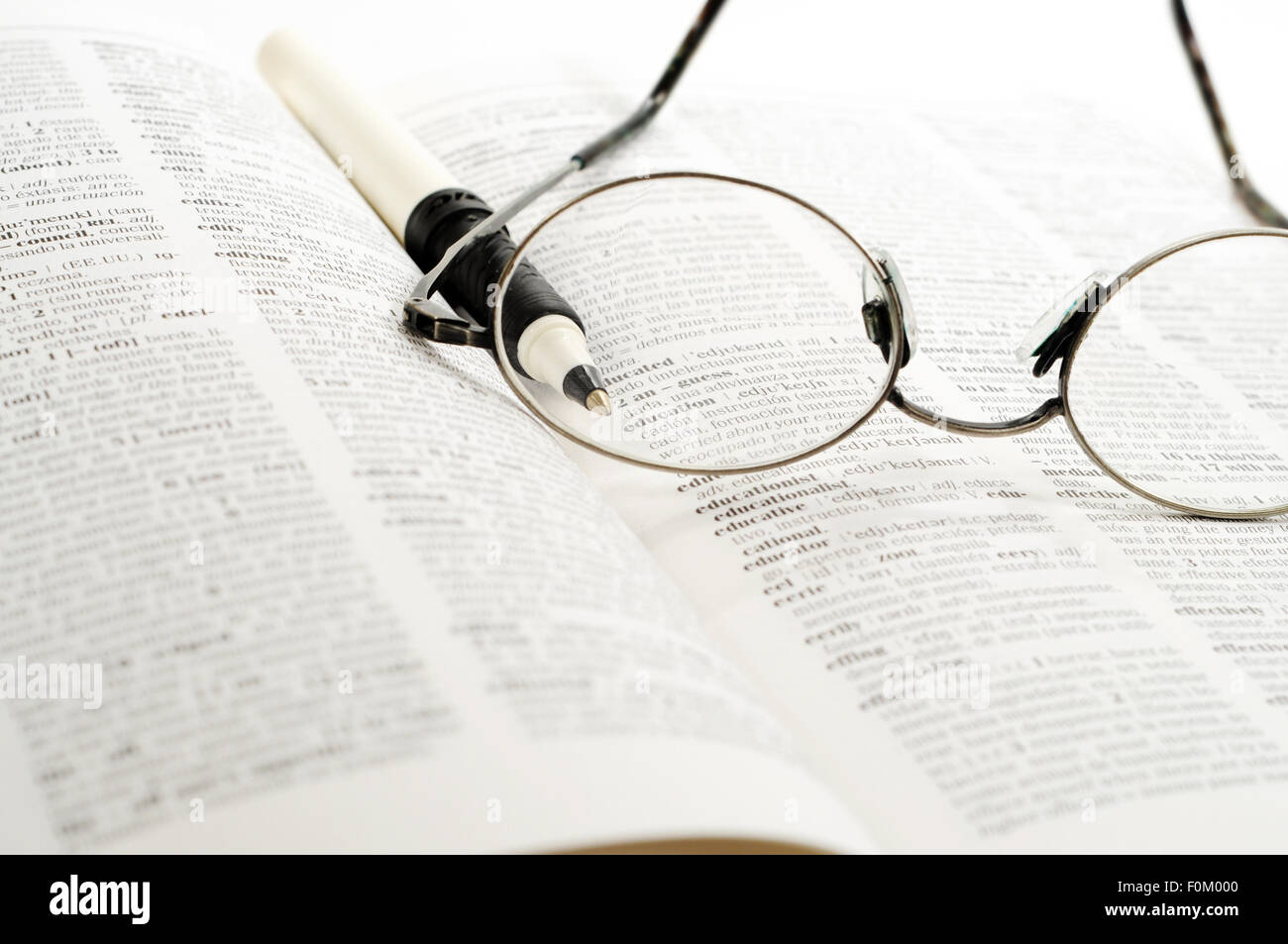 Lesebrille und Stift über einem Buch Stockfoto