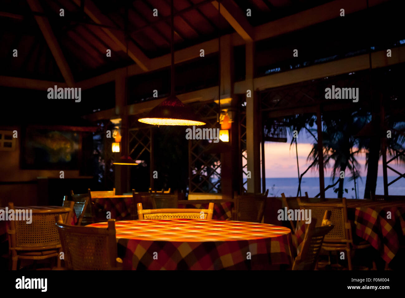 Blick auf leere Esstische in einem Restaurant im Hintergrund des Strandes von Lovina vor Sonnenuntergang in Singaraja, Buleleng, Bali, Indonesien. Stockfoto