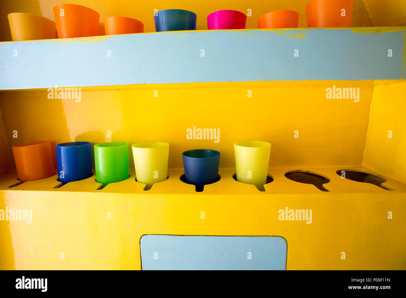Kunststoff-Glas in verschiedenen Farben auf gelbem Hintergrund gespeichert Stockfoto