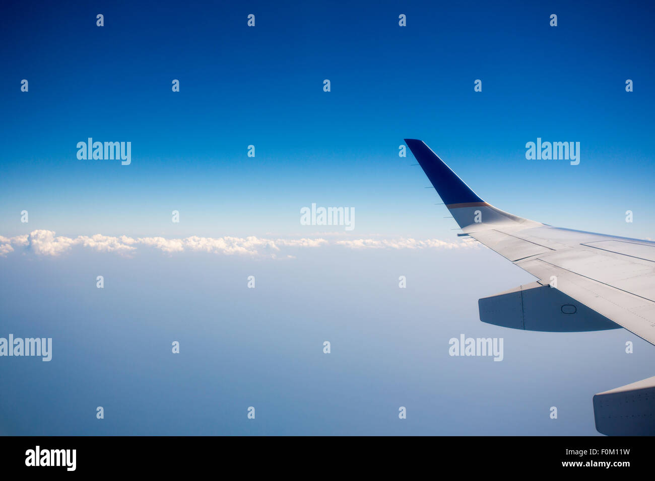 Blick auf Jet Flugzeug Flügel mit kristallklarem blauen Himmel im Hintergrund und Wolken mit Textfreiraum. Stockfoto