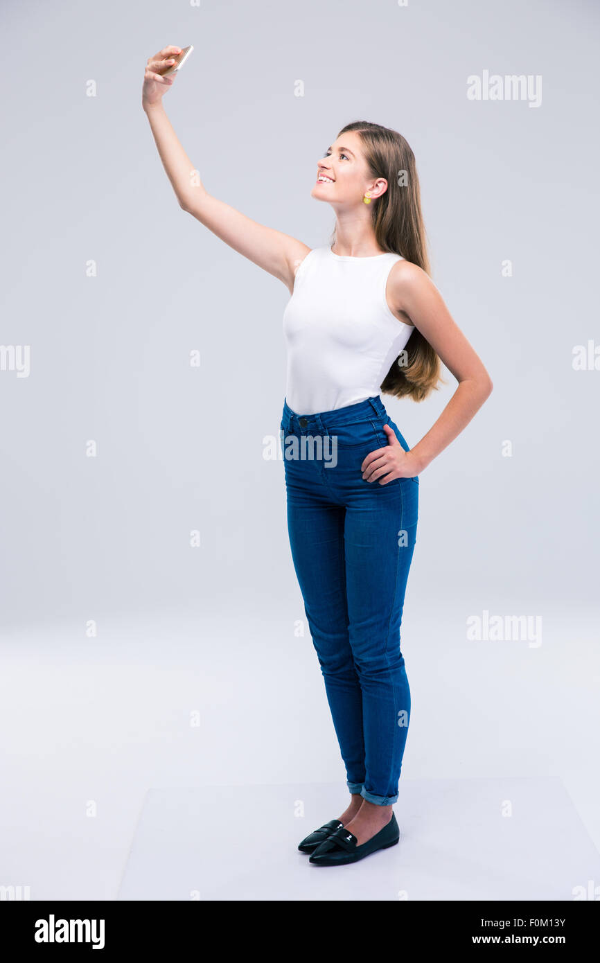 In voller Länge Portrait von glücklich weibliche Teenager machen Selfie Foto auf Smartphone isoliert auf weißem Hintergrund Stockfoto