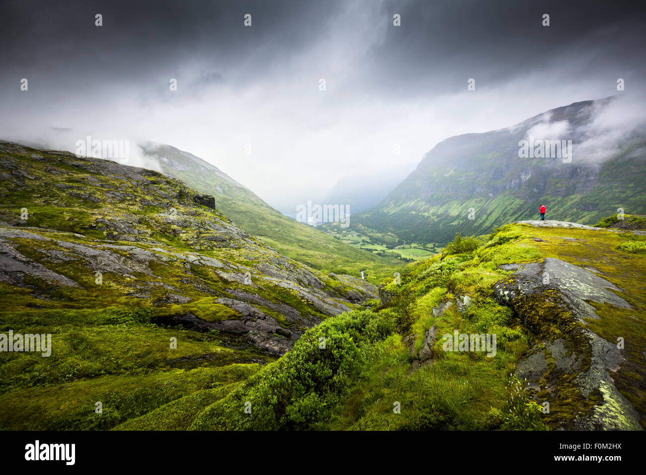 Einziger Mann auf einem Felsvorsprung in den Bergen, Geirangerfjord, Norwegen Stockfoto