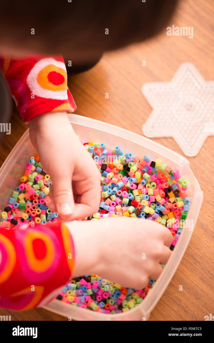 Kleines Mädchen (5 Jahre) spielen mit bunten Kunststoff-Perlen. Ein Moment der Kindheit Spaß und Freizeit. Stockfoto
