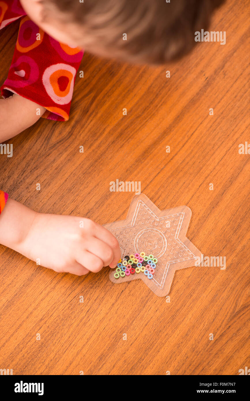 Kleines Mädchen (5 Jahre) spielen mit bunten Kunststoff-Perlen. Ein Moment der Kindheit Spaß und Freizeit. Stockfoto
