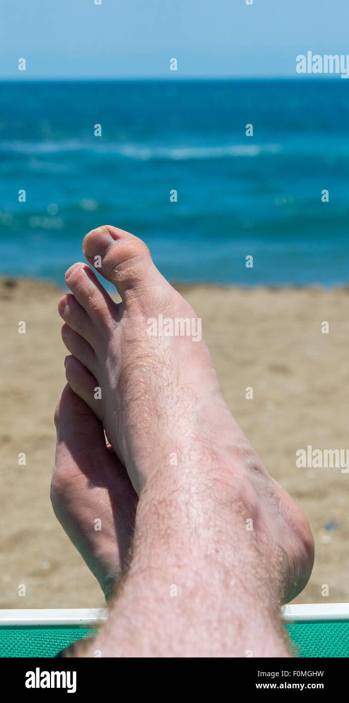 A mans Füße am Rande eine Sonnenliege am Strand im Süden Spaniens Stockfoto