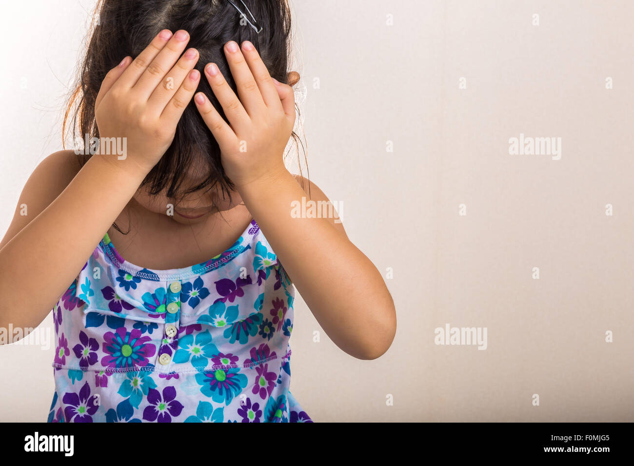 Kleines Mädchen deckt ihre Stirn mit Händen, wenn enttäuscht fühlen. Stockfoto