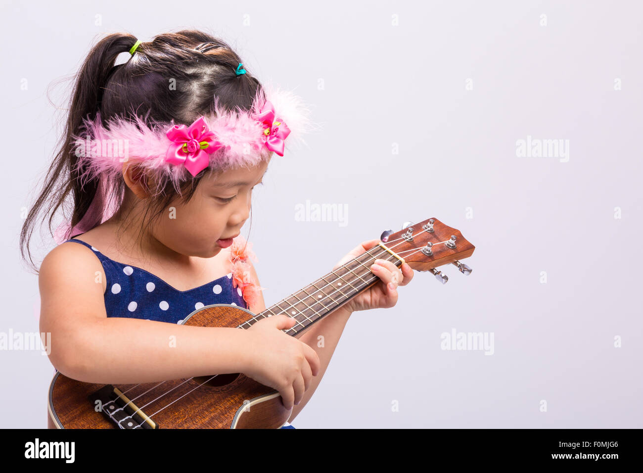 Kleines Mädchen mit ihrer Ukulele Musik Saiteninstrument. Stockfoto
