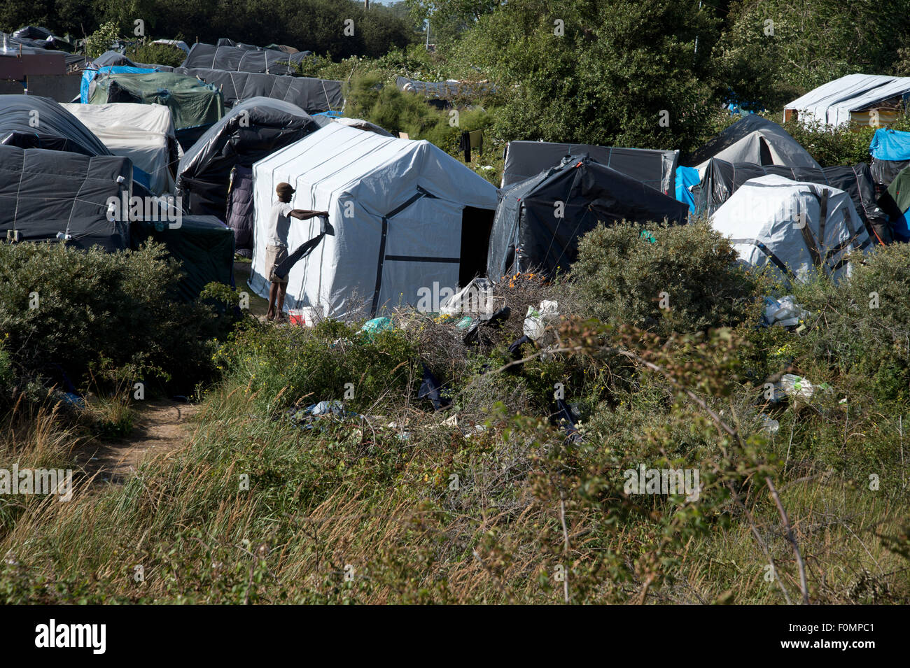 Migration Calais.The Dschungel-Camp. Ein Mann ringt, seine Kleidung nach dem Waschen sie vor einigen provisorischen Hütten. Stockfoto
