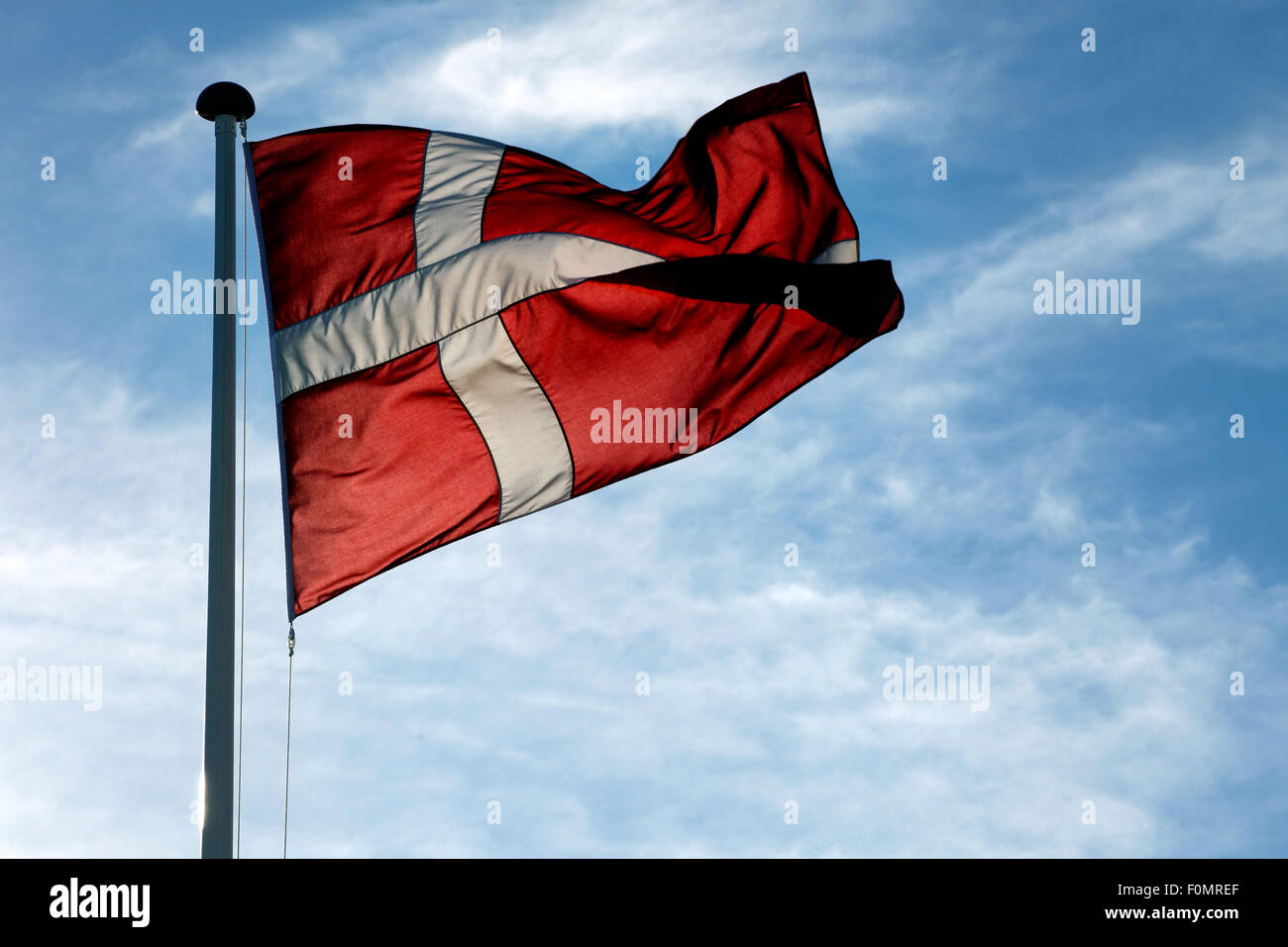 Die dänische Flagge Dannebrog winken gegen blauen Himmel Stockfoto