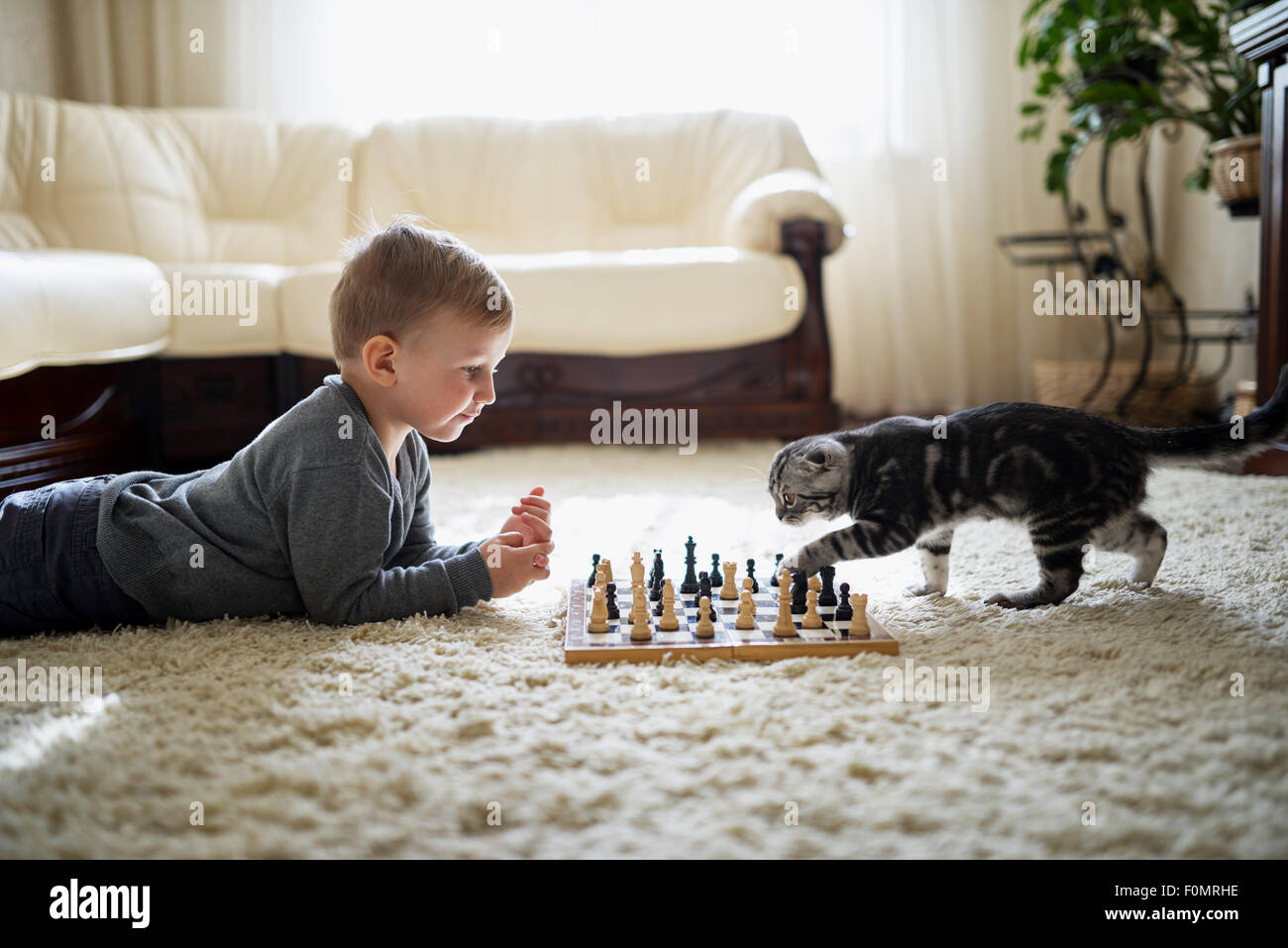 kleiner Junge spielt Schach am Boden liegend Stockfotografie Alamy
