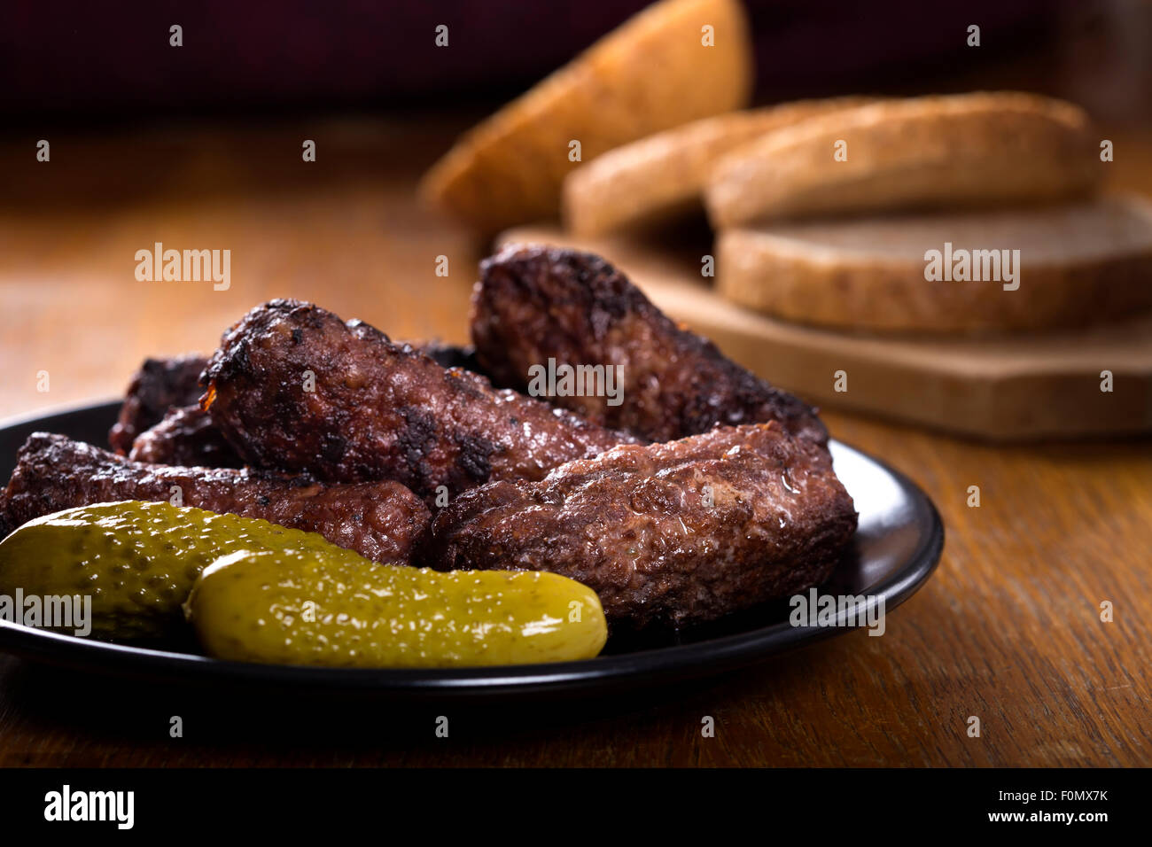 Traditionelles Essen "Mici" Würzige Frikadellen auf Teller mit sauren Gurken Stockfoto