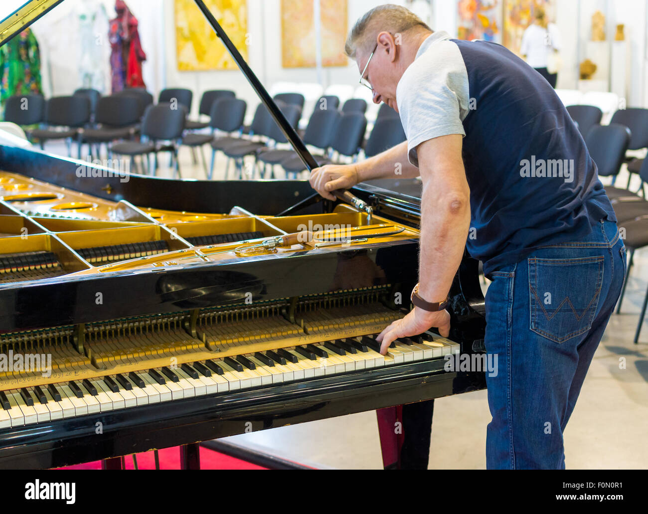 Professioneller Klavierstimmer arbeitet an einem Flügel vor einer musikalischen Aufführung Stockfoto