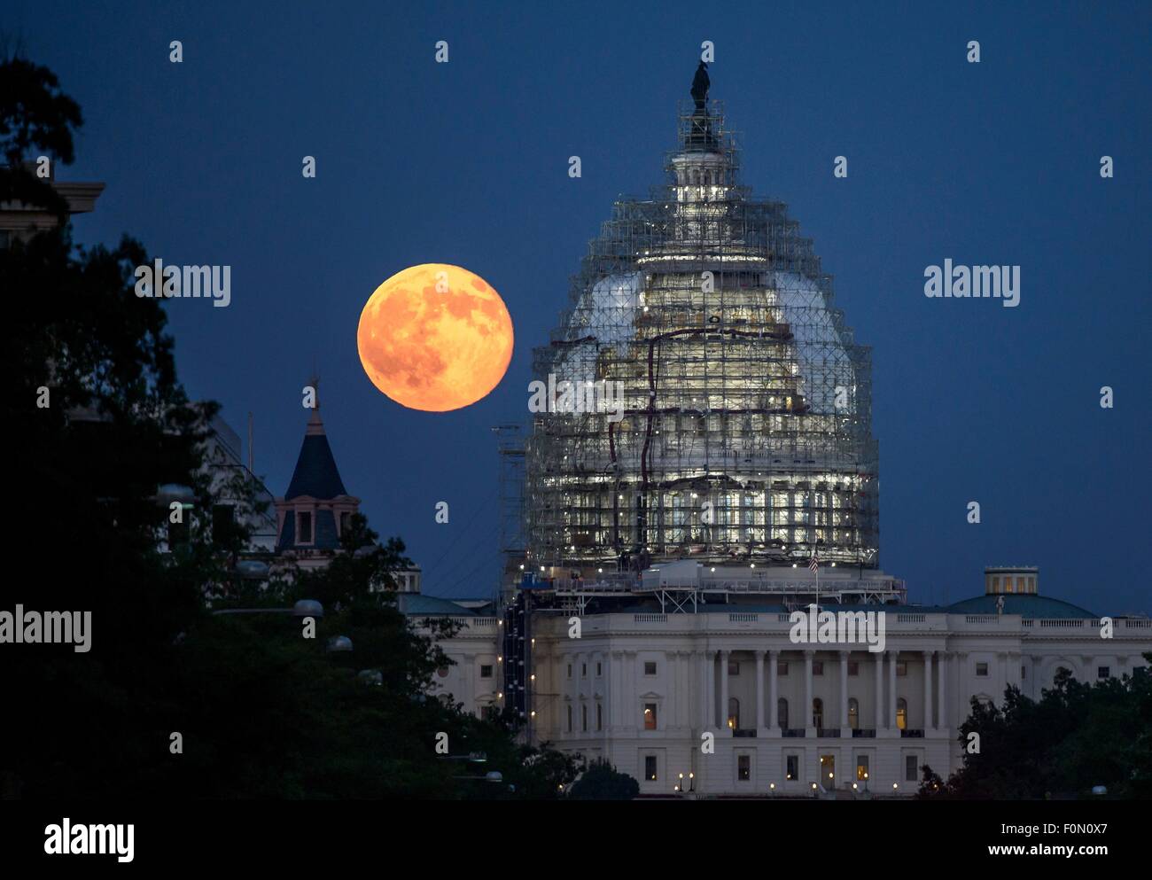 Ein zweite Vollmond für den Monat Juli steigt hinter der Kuppel des Kapitols, die derzeit im Gerüstbau für Restaurierung 31. Juli 2015 in Washington, DC gezwängt. Zwei Vollmonde im selben Monat gekennzeichnet häufig als ein Blue Moon. Stockfoto