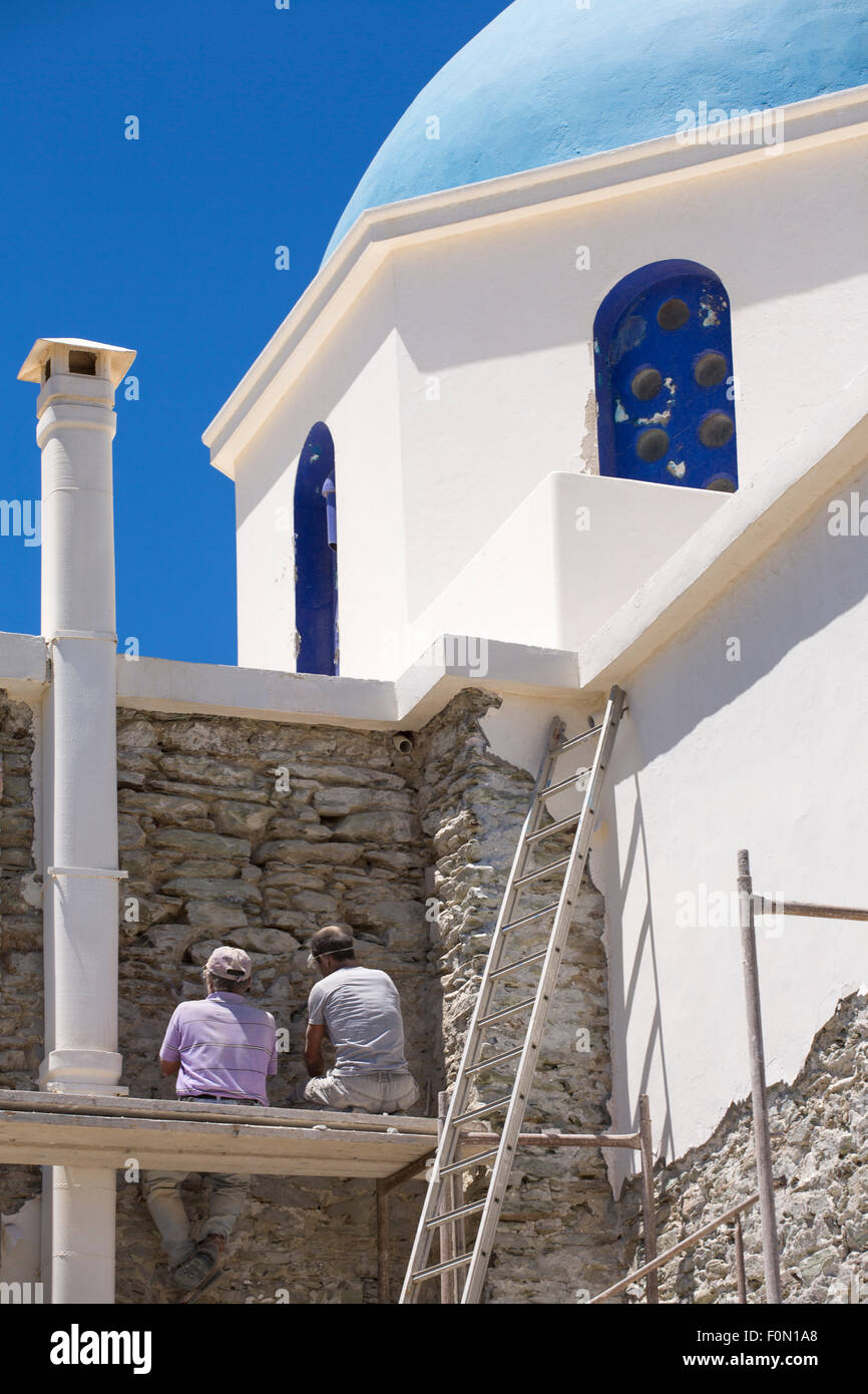Zwei unbekannte Männer bei Arbeiten an der Fassade der weißen orthodoxen Kirche der Panagia von Chora, Insel Folegandros Stockfoto