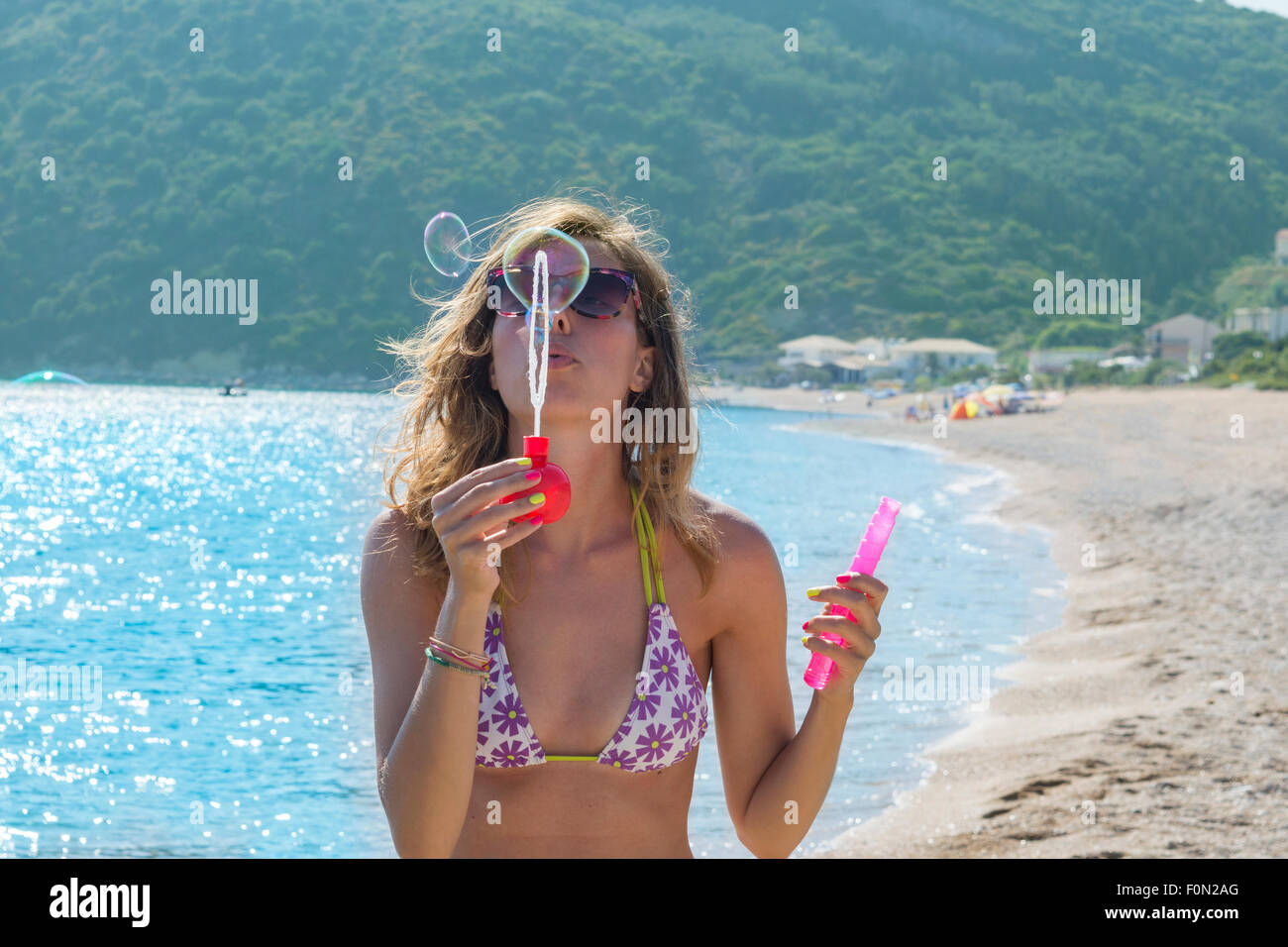 Junges Mädchen bläst Seifenblasen am Strand. Sommerspaß Stockfoto