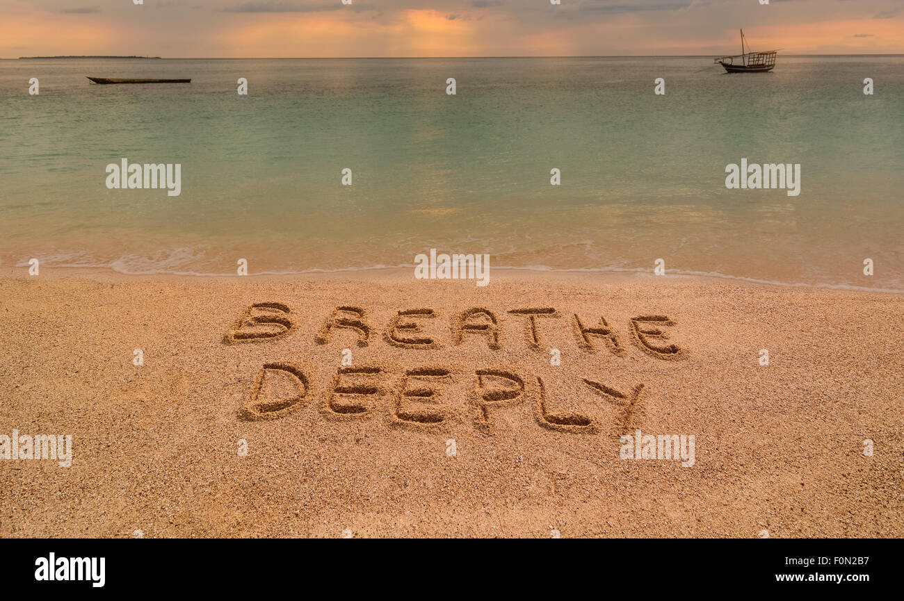 Auf dem Foto einen Strand bei Sonnenuntergang in Sansibar wo gibt es eine Inschrift auf dem Sand "Atmen Deeeply". Stockfoto