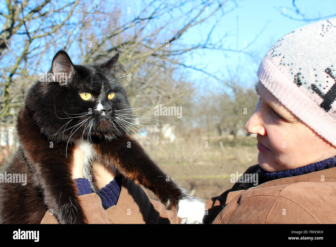 Frau betrachten schwarze Katze mit weißen Krawatte im Frühjahr Stockfoto