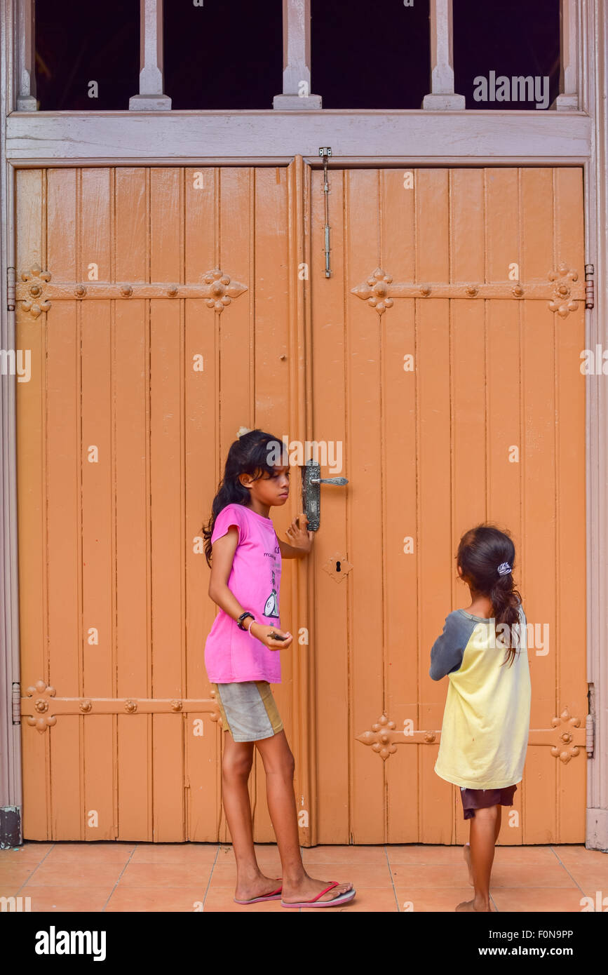 Kinder vor der alten Tür der Kirche des heiligen Ignatius Loyola, einer alten katholischen Kirche im Dorf Sikka, Lela, Insel Flores, Indonesien. Stockfoto