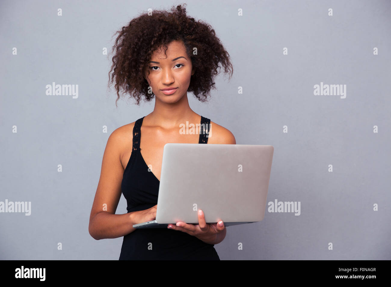 Porträt einer schönen Afro amerikanische Frau mit Laptop auf grauem Hintergrund. Blick in die Kamera Stockfoto