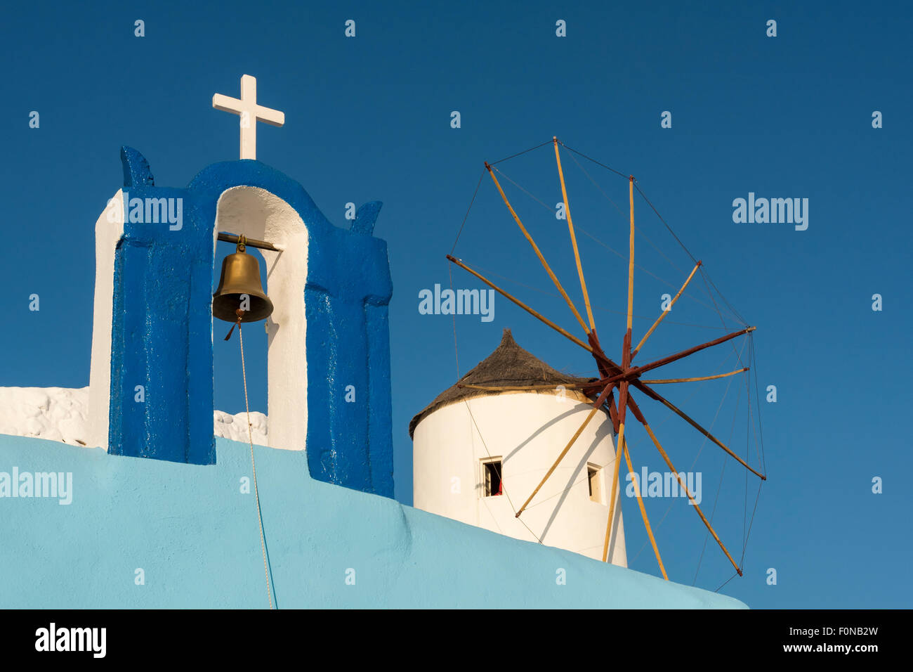 Glockenturm der Kirche Agios Apostolos (St. Apostel) und Windmühle, Oia, Santorini, Griechenland Stockfoto