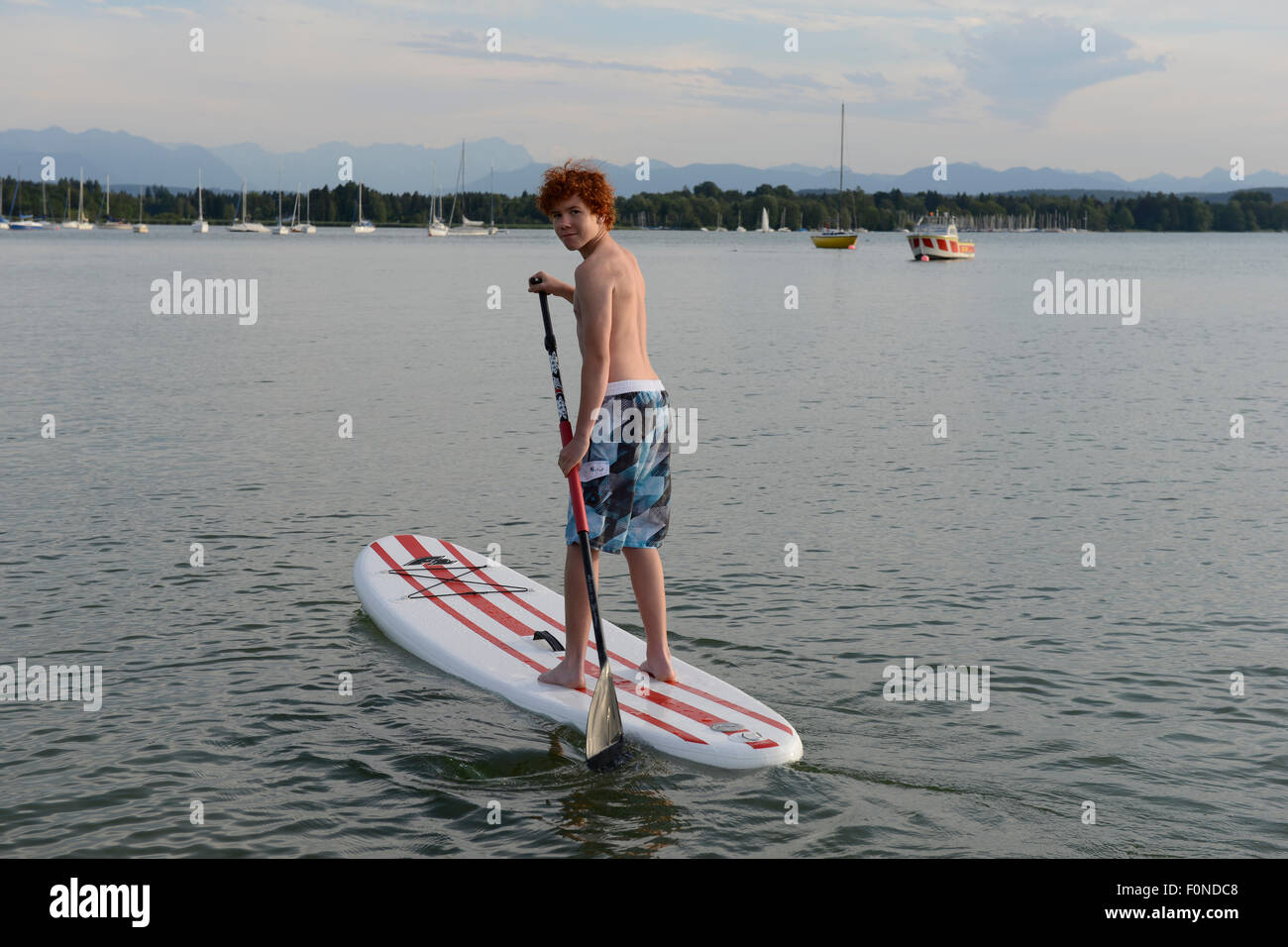 Junge, stand up Paddle boarding, SUP, St. Heinrich, Starnberger See, Fuenfseenland, Upper Bavaria, Bavaria, Germany Stockfoto