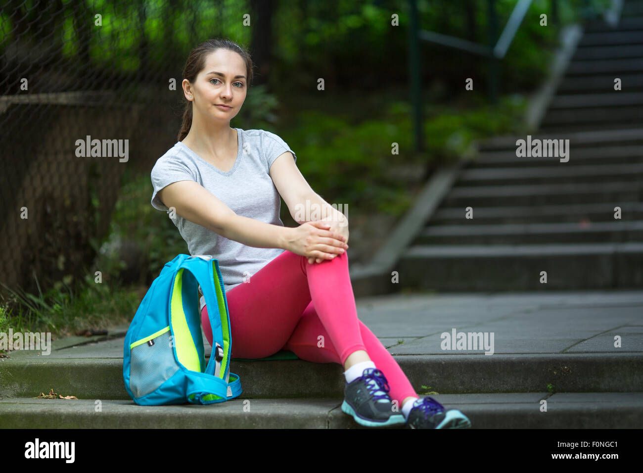 Porträt der jungen Sportlerin nach dem Training sitzen auf der Treppe im Park. Stockfoto