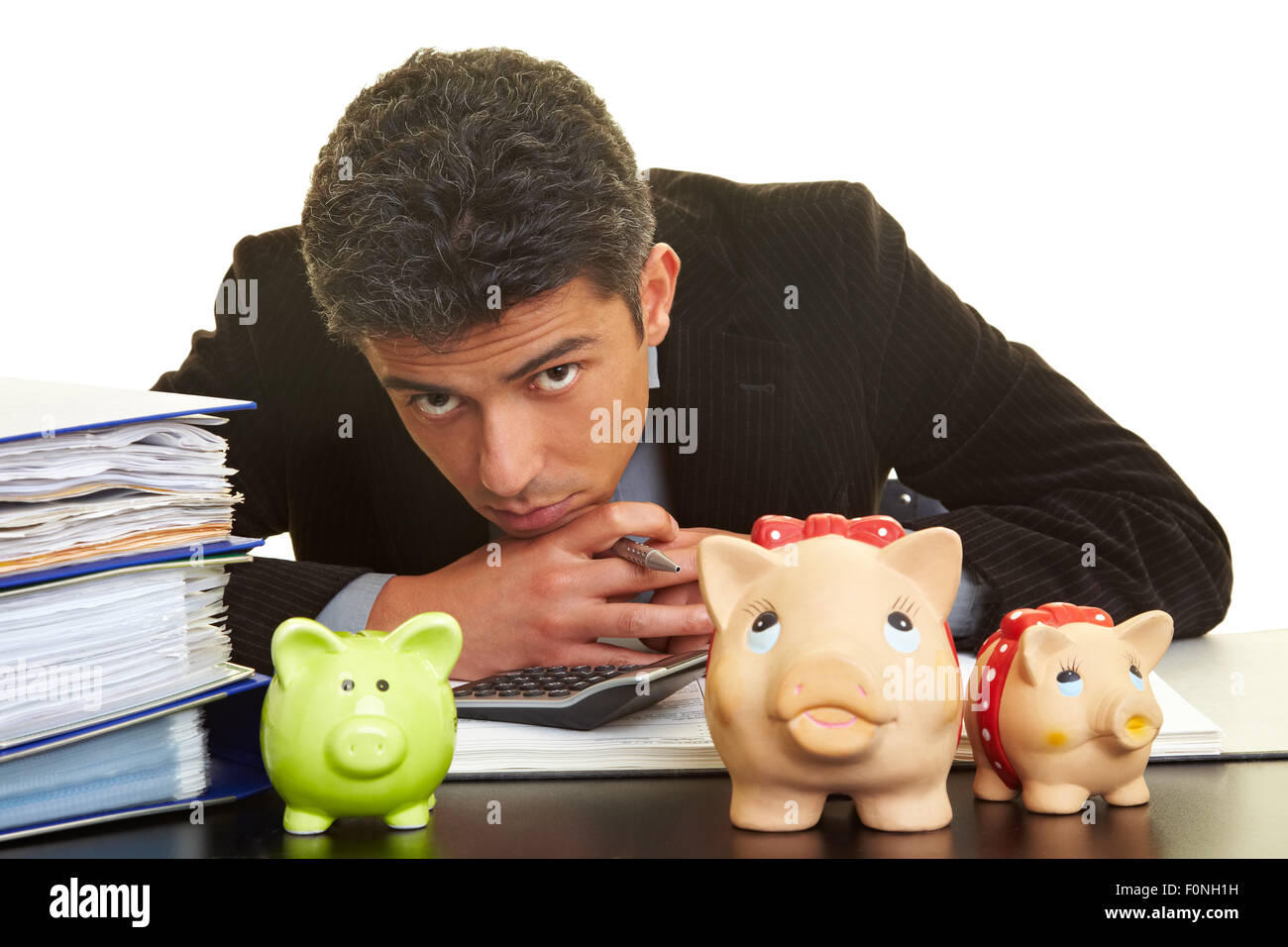 Kaufmann an seinem Schreibtisch hinter drei Sparschweine Stockfoto