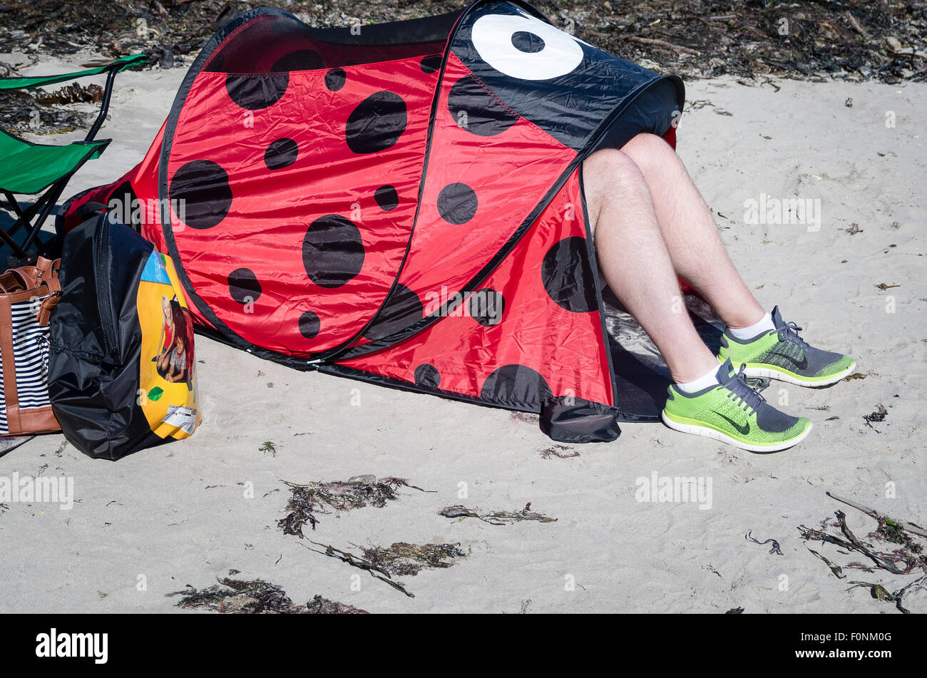 Beine aus unter Größe Sonnenschutz an einem öffentlichen Strand in England UK Stockfoto
