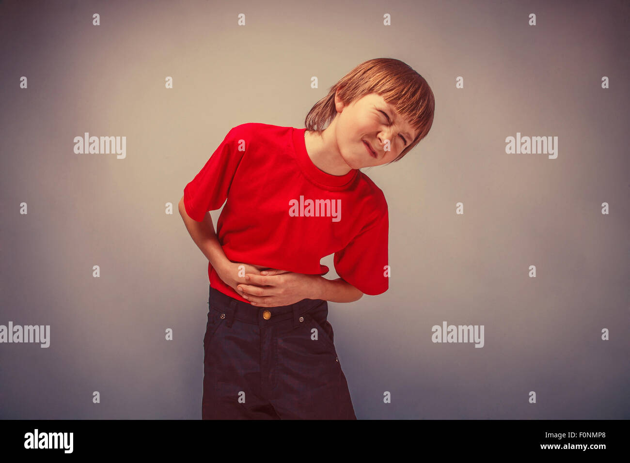 Junge Teenager zwölf Jahre im roten Hemd Bauchschmerzen, gastriti Stockfoto