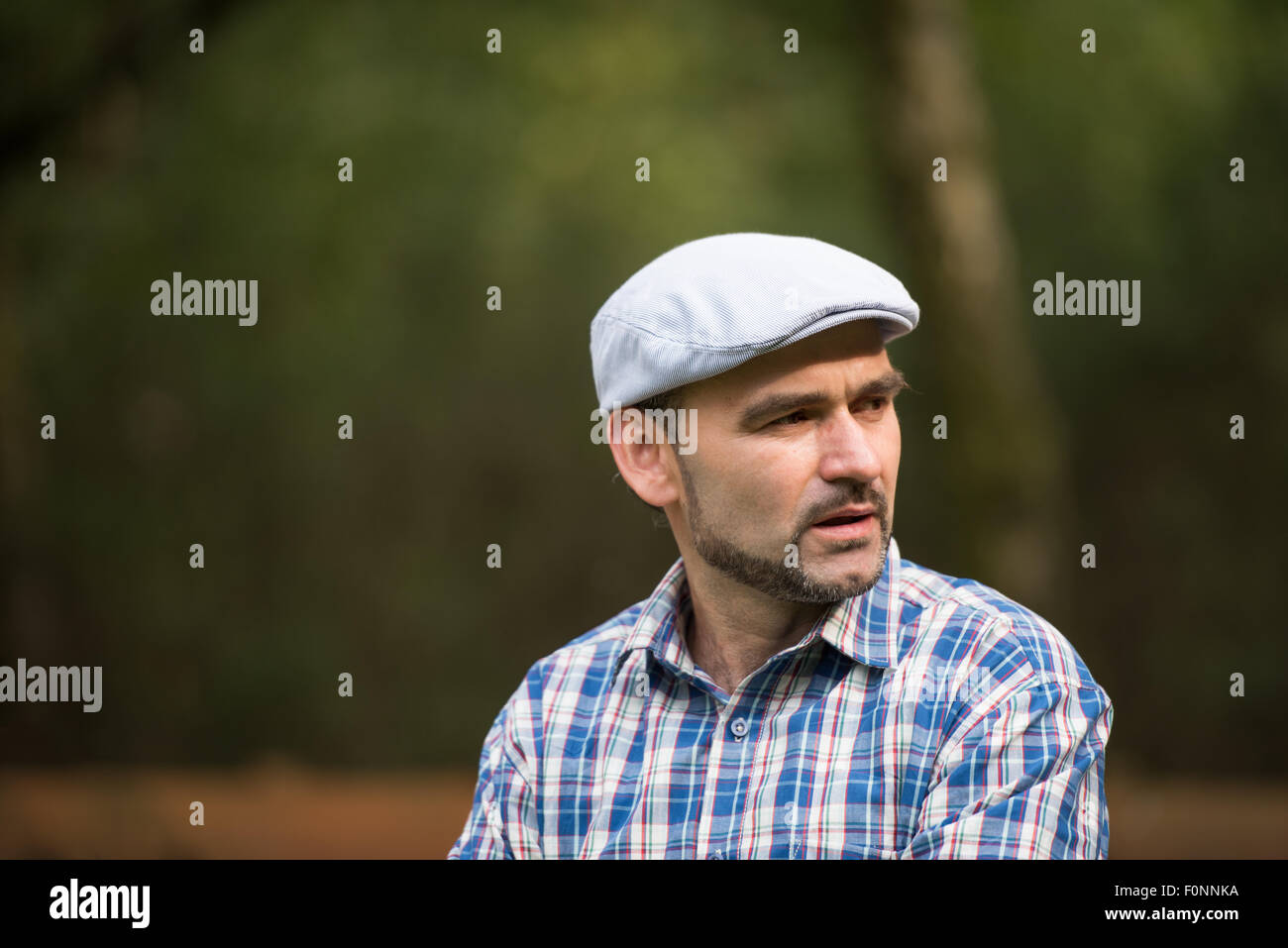 Mittleres Alter bärtiger Mann mit Low-Profile-Mütze Blick zur Seite Stockfoto