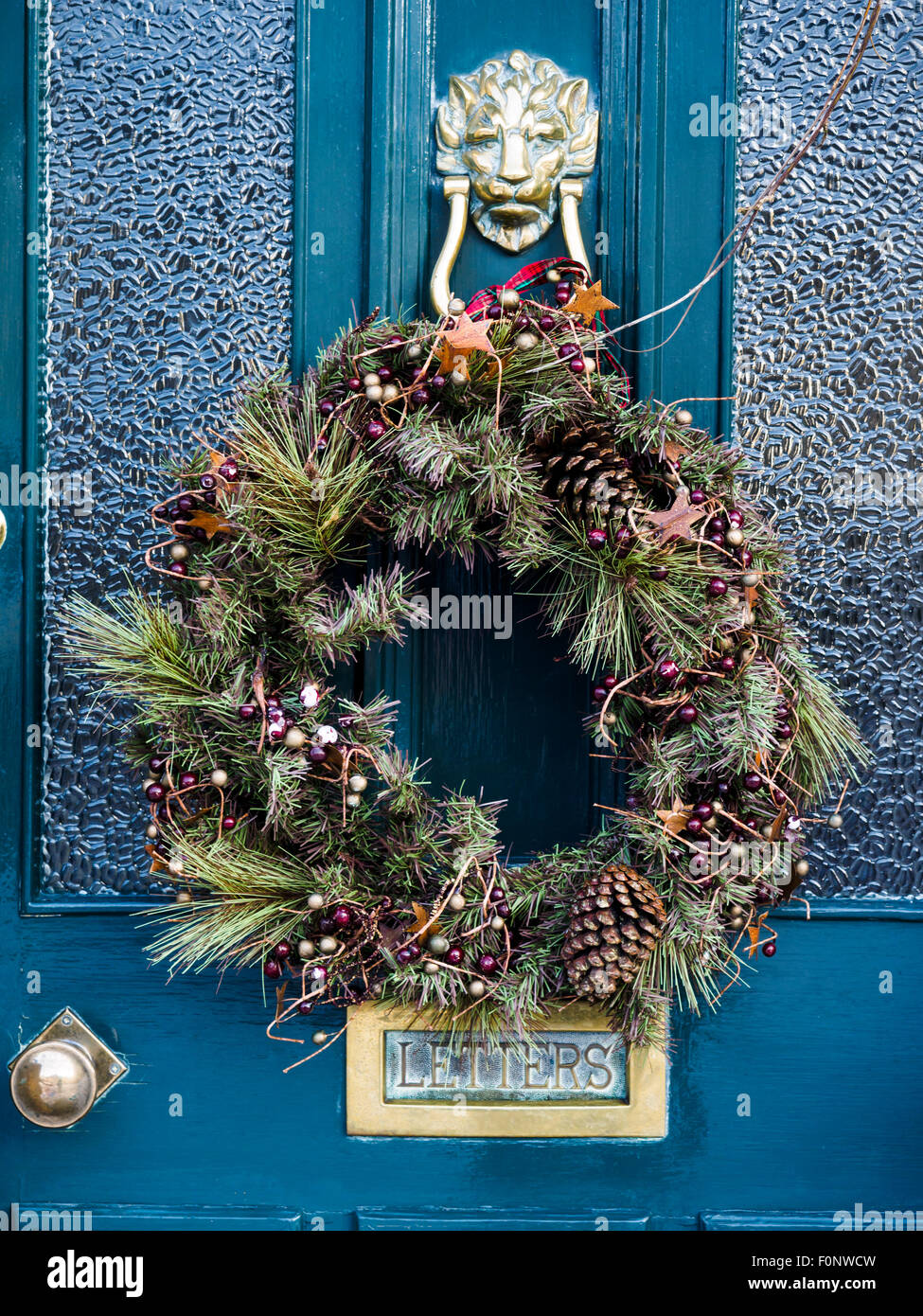 Dekorationen/Adventskranz hing an blaue Tür mit Messing-Armaturen-England Stockfoto