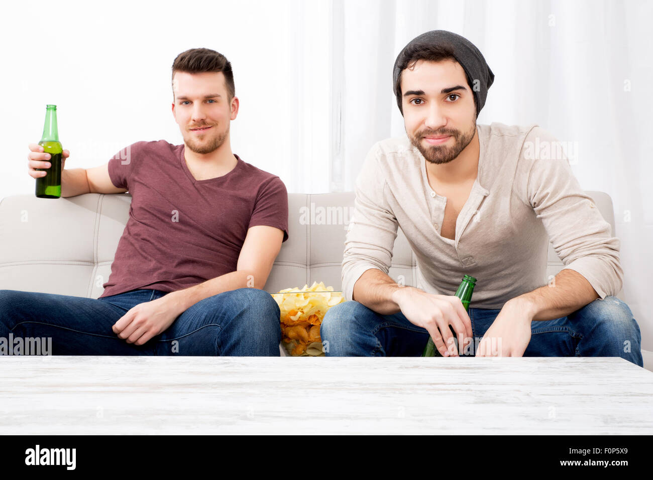 Zwei Jungs vor dem Fernseher, trinken Bier, Chips zu Hause essen Stockfoto