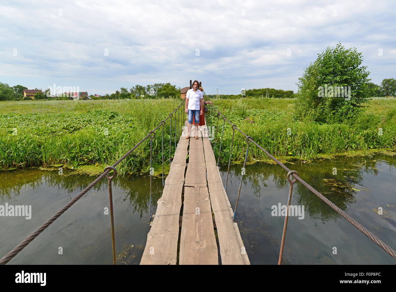 zwei Personen gehen auf einer Hängebrücke über den Fluss Stockfoto